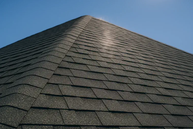 Summer sun on a dark roof Hard summer sunlight falling across a dark asphalt roof with heat haze.