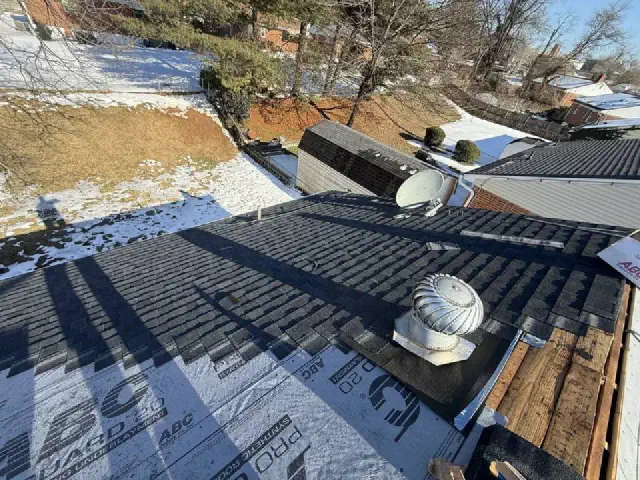 New dark shingles going on over gray underlayment around a turbine vent.