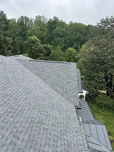 New gray shingle roof with valleys meeting a small metal roof section.