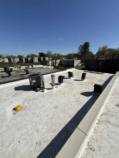 Worn white flat roof with vents and heating and cooling units on top.